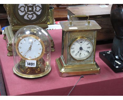 A XIX Century German Brass Carriage Clock, with a circular dial, Roman numerals; together with a Kinder mantel clock under a 