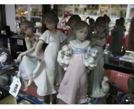 A Lladro Girl on the Phone, girl with puppies, and girl holding a cat, plus two Nao figurines.(5)