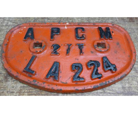 A cast metal engine plate, A.P.C.M. (Associated Portland Cement Manufacturers) 27T LA224; used on a narrow gauge railway