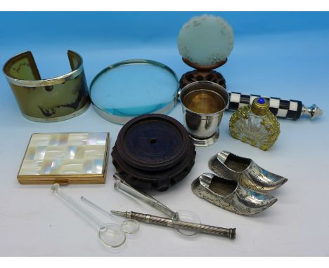 A magnifying glass, horn bangle, compact, hardstone disc on a wooden stand, etc.