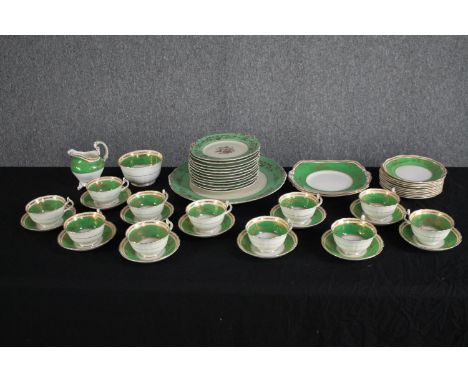 A German porcelain tea set for eleven people. 1930s Konig teacup &amp; saucer, plates and creamer. In green and gilt edged de