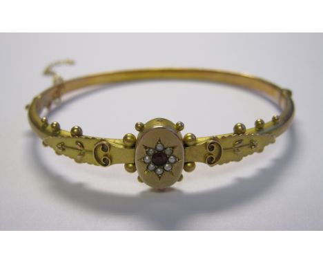 A 9ct gold hinged Bangle the front set ruby within frame of seed pearls