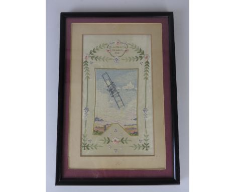 A polychrome stitched Picture of a First World War type bi-plane against clouds. In cartouche 'G.W. Beatty Hendon 1913'. Beat
