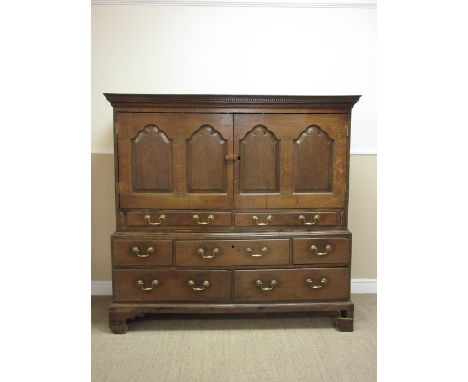 An antique oak Press Cupboard the upper section fitted pair of fielded panel doors beneath dentil frieze cornice, the lower s