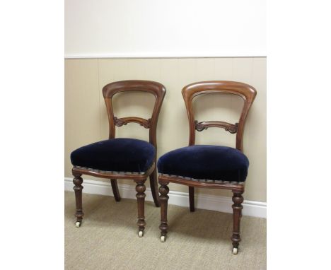 A set of six Victorian mahogany balloon back Dining Chairs mounted upon turned supports and ceramic casters