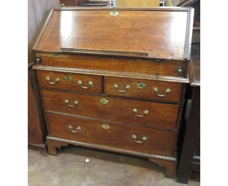 An antique oak Bureau with moulded edgings on bracket supports