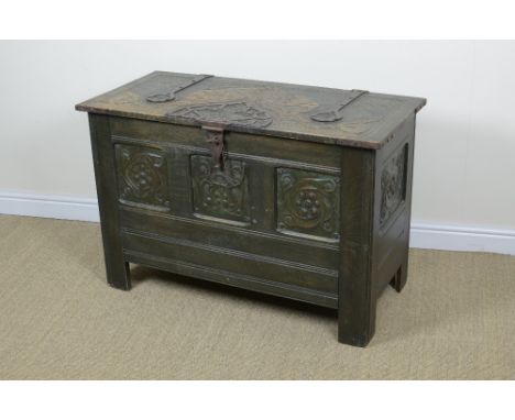 An Arts & Crafts carved Chest with metal strapwork, embossed panels and enamel to the hinged cover including a decorative int