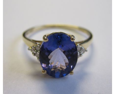 A Tanzanite and Diamond Ring claw-set oval-cut tanzanite, 2.50cts, between trios of brilliant-cut diamonds in 14ct gold, ring