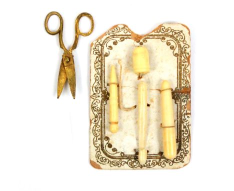 A rare card of miniature bone sewing accessories for a doll, the card with gilt printed border and stitched with stiletto, cr