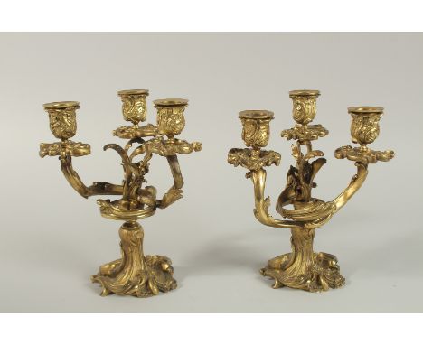 A GOOD PAIR OF 19TH CENTURY GILDED BRONZE, TRIPLE LIGHT CANDLESTICKS with scrolls, flowers and acanthus. 21cm high.