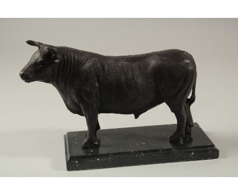 A BRONZE BULL on a marble base. 23cms long.