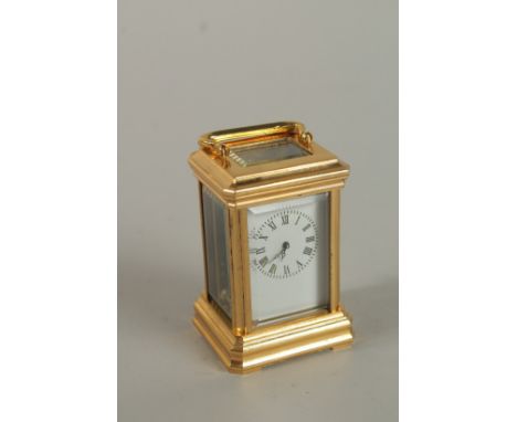 A MINIATURE BRASS CARRIAGE CLOCK with black and&nbsp; white dial and carrying handles. 7cms.