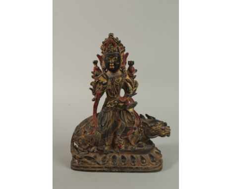 A GILT BRONZE DEITY seated upon a mythical beast. 33cm high.