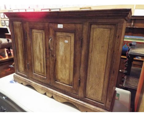 A rustic pine low cabinet fitted with a pair of panel doors enclosing a single shelf and raised on a plinth base