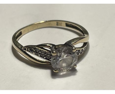 A 9 CARAT GOLD RING WITH A LARGE CENTRE CLEAR STONE AND SMALLER TO THE SHOULDERS 