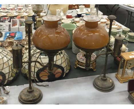 A PAIR OF VINTAGE BRASS OIL LAMPS WITH AMBER GLASS SHADES CONVERTED TO ELECTRICITY - WILL NEED REWIRING, ONE CHIMNEY MISSING 