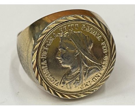 A YELLOW METAL RING WITH A GOLD COLOURED COIN 