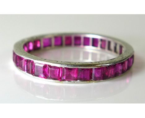 A ruby and platinum eternity ring, the Greek key engraved band set with twenty eight step cut rubies, a/f one missing, the ba