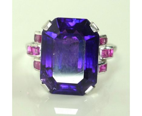 An Art Deco style amethyst, ruby and platinum dress ring, the central emerald cut amethyst of 15.6 by 11.6 by 8.35mm approxim