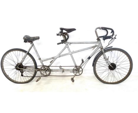 A vintage lady back tandem bicycle by The Hercules Cycle & Motor Co, with silver painted frame, drop handlebars and black mud