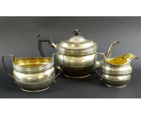 A George III silver three piece tea set, comprising teapot, milk jug and sucrier, all boat shaped with lobed bellies and silv