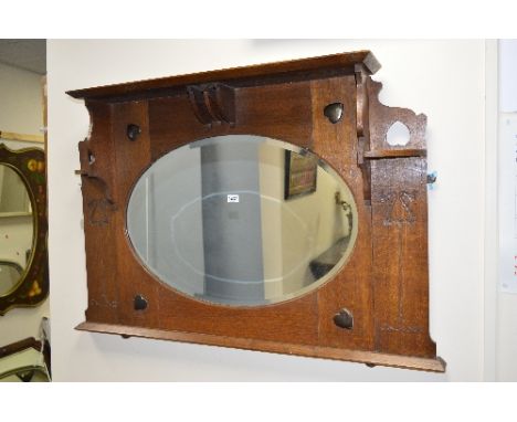 AN ARTS & CRAFTS OAK OVERMANTEL MIRROR, the overhanging cornice supported on two corner shelf brackets and central shaped mou