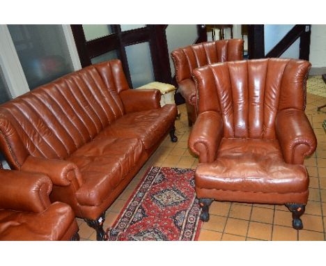 A REPRODUCTION VICTORIAN STYLE BROWN LEATHER THREE PIECE SUITE, comprising of a two seater sofa and a pair of armchairs, on b