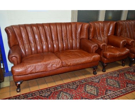 A REPRODUCTION VICTORIAN STYLE BROWN LEATHER TWO PIECE SUITE, comprising of a two seater sofa and an armchair, on ball and cl