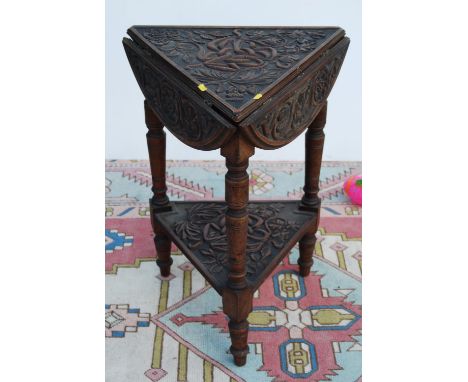 Carved oak occasional table, the triangular top with demi-lune drop flaps, on baluster turned legs united by a shelf, 45cm wi