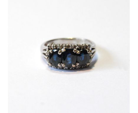 Dress ring with three oval sapphires within a border of tiny eight-cut diamonds, in white gold, probably 18ct, size M½, 4.7g.