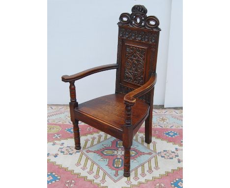 Jacobean-style oak throne chair, with crown carved finial over floral carved back panel, open arms, plank seat, on baluster l