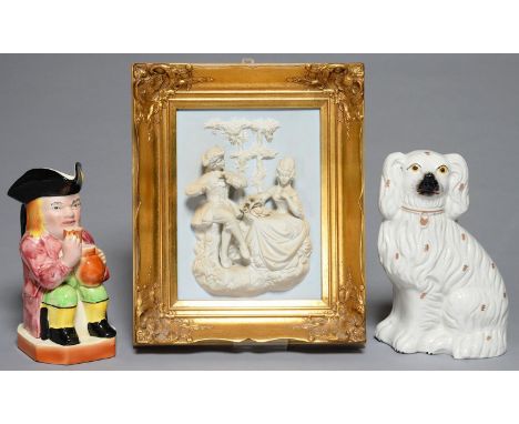 A STAFFORDSHIRE EARTHENWARE MODEL OF A SPANIEL, SECOND HALF 19TH C, 24CM H, AN AVON WARE TOBY JUG AND A BISCUIT PORCELAIN PLA