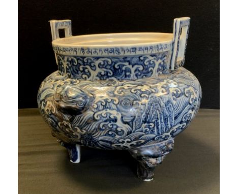 A Chinese tripod bowl planter, two square handles, decorated with cresting waves and mask head medallions, conforming feet, 2