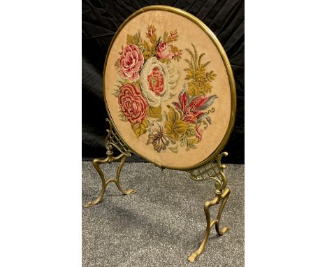 A Victorian brass and tapestry fire-screen, circular screen, pierced brass supports, Art nouveau-form legs, 70cm high x 50cm 