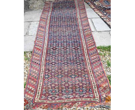 An old Caucasian runner with repeating diamond medallions on navy field, and multi-coloured chevron border, 345 x 97 cm 