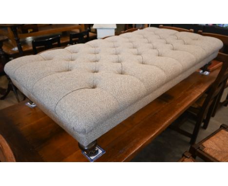 A Chesterfield footstool with buttoned diamond patterned fabric on turned oak legs and brass casters, 155 cm x 80 cm x 35 cm 