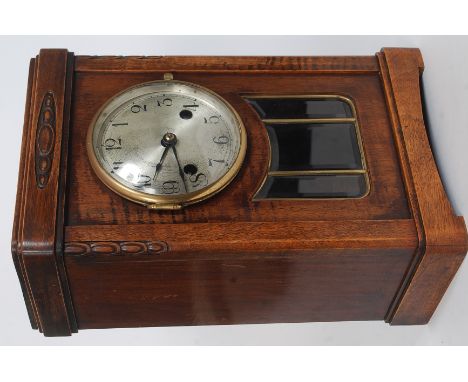 An oak cased 1930's mantle clock, brass face with eight day movement striking on a coiled spring. The oak case with glass pen