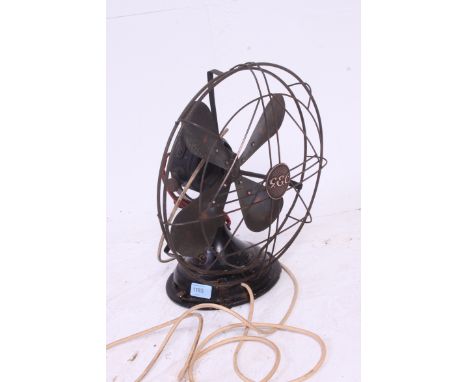 A vintage 1930's Art Deco GEC black metal industrial office fan having copper blades with cage, gold notation for GEC to base