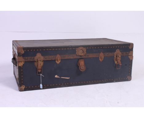 A large vintage blue shipping trunk, with metal clasps and hinges, with shipping / travel labels affixed to exterior. 