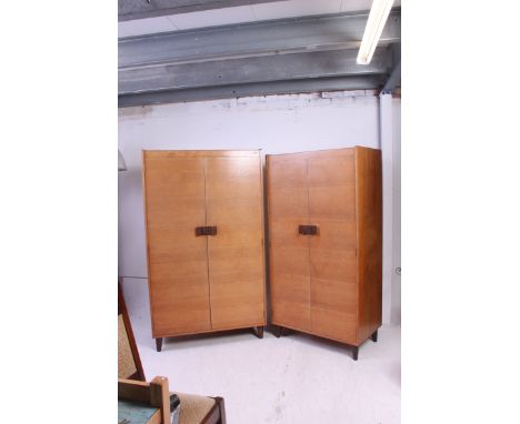 A Gordon Russell of Broadway, Worcestershire pair of oak wardrobes. Both raised on angled tapered supports with twin doors ha