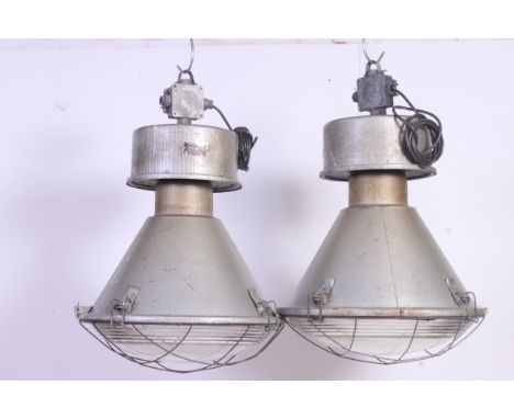 A pair of vintage Zaklady Metalow Industrial large factory pendant lights complete with the glass shades and cages with origi