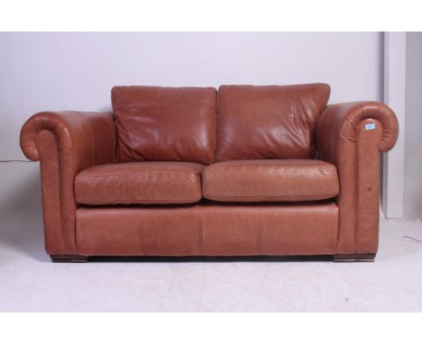 A Thomas Lloyd 2 seat brown leather chesterfield sofa settee having turned stub mahogany feet with shaped arms and elbow rest