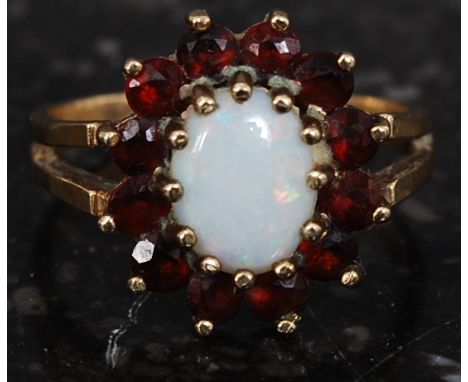 A ladies 9ct gold opal ring with ruby garnet stone surround set on plain shank. Total weight