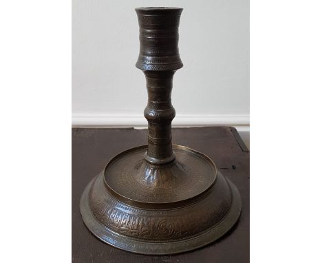 A large antique Islamic copper alloy candlestick, decorated overall with stylised foliate decoration and script, 9" high.