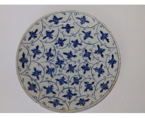 An early 19thC blue &amp; white delft dish painted stylised flowerheads on scale ground, 9.5" diameter.