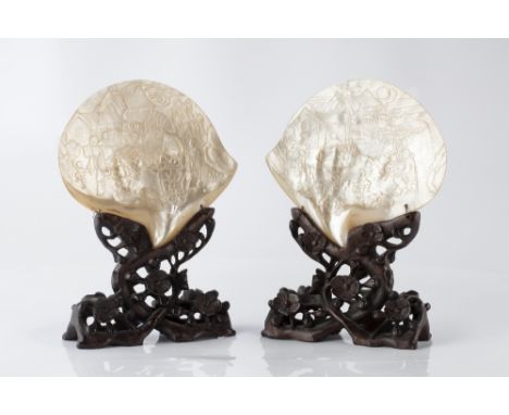 A pair of Chinese mother of pearl carved shells on stands 19th Century each with scenes of children playing on a terrace, the