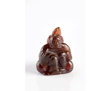 A Chinese amber small carved seated figure late 19th Century the figure set against an urn with pomegranate and with tied dou