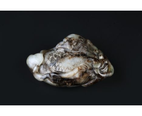 A Chinese white and brown jade pebble Ming period carved as a sleeping bird and a lotus flower on a lotus leaf, 7.5cm