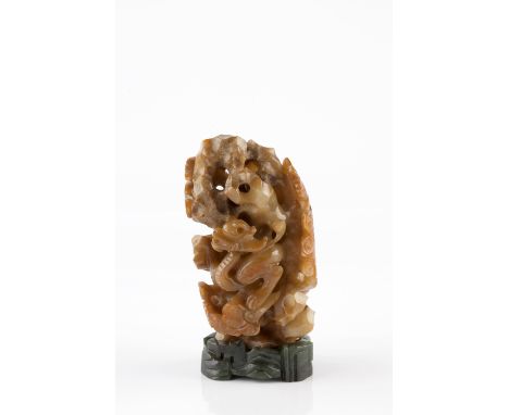 A Chinese carved pale agate 19th Century pierced and carved as a gnarled boulder within which a chilong dragon on scrolling c