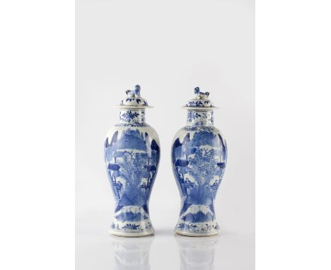 A pair of Chinese blue and white baluster vases and covers 19th Century each with landscape scenes, Kangxi mark, 28cm